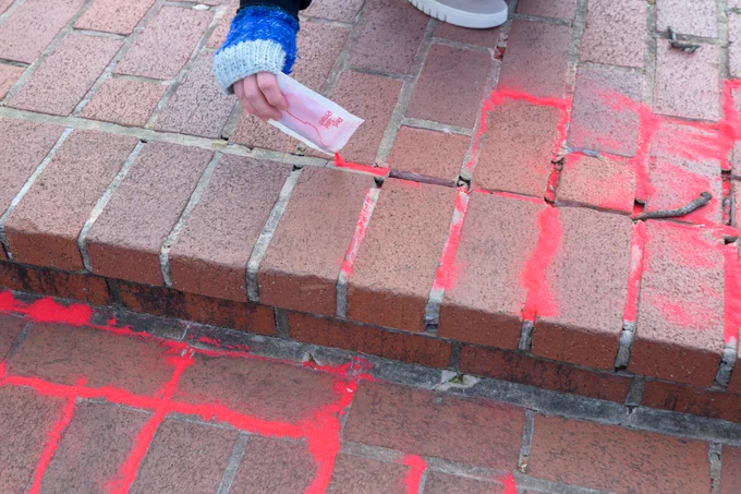 Photo of red sand being poured into sidewalk cracks during a Red Sand Project at BWI Thurgood Marshall Airport.