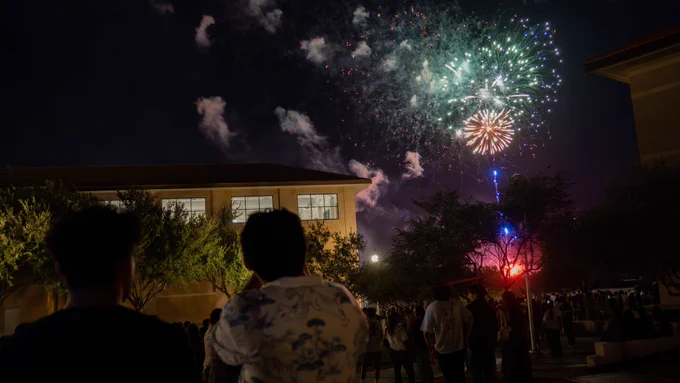 TAMIU Students watch a firework show on campus at night.
