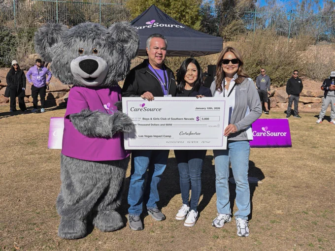 Cuddles and three people holding a large check from CareSource for $5,000 to the Boys & Girls Club of Southern Nevada at an outdoor event.