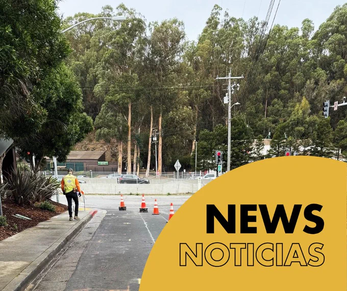 Image of a person in a yellow jacket walking on a sidewalk along a road with construction cones and trees in the background, with the text 'NEWS NOTICIAS' overlaying in yellow.