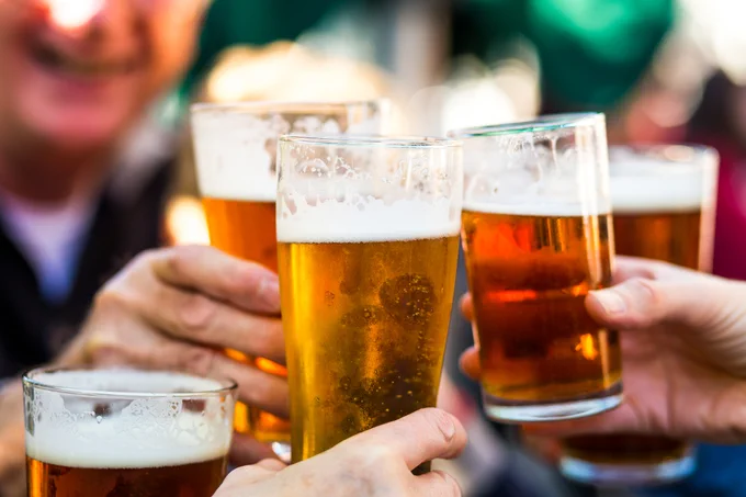 Close-up of several people toasting with glasses of beer.