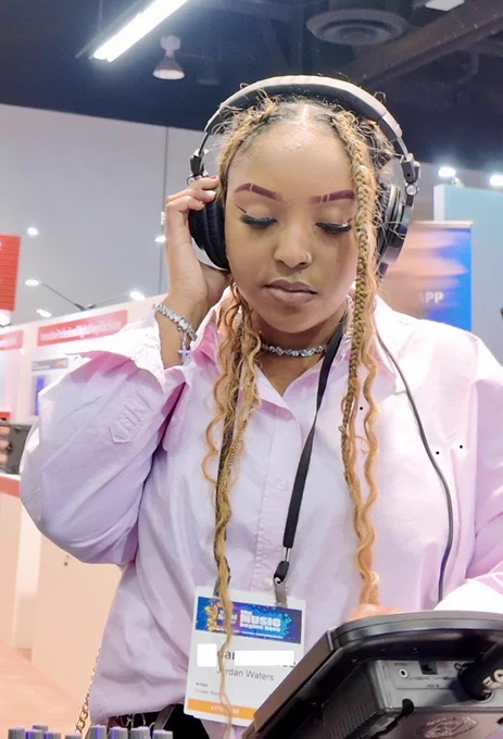 Trade show attendee wearing headphones adjusts a Hear Back PRO Mixer.