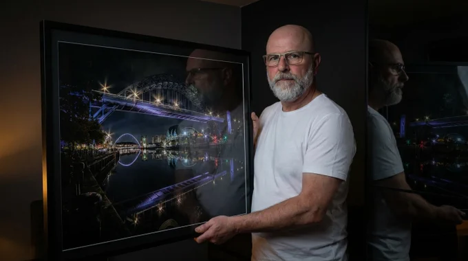 Michael Paul Bennett holding a large framed print of his award winning Tyne Bridge at Night Photograph