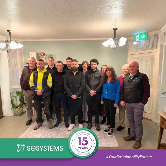 SE Systems team members and community representatives standing together indoors during the Good Shepherd project visit.
