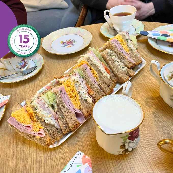 Table set with tea, sandwiches and cups during a community gathering at the Good Shepherd media day.