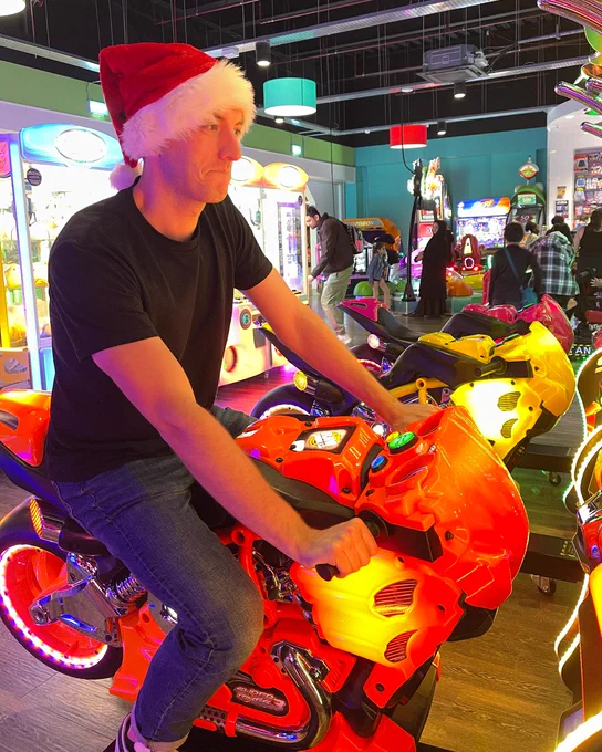 Person wearing a Santa hat riding a motorcycle arcade game at Funstation in Xscape Milton Keynes