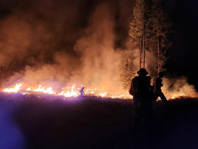 Firefighters work on a night burn operation with low-lying plants on fire and putting off smoke. Firefighters work at night on the Lynx Mountain Fire in northeast Washington.