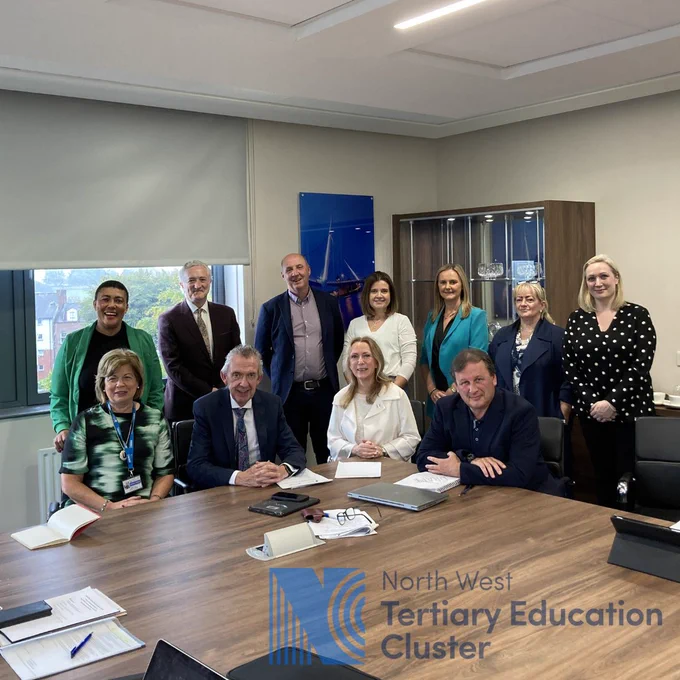 Eleven members of the Steering Group Committee seated around Board room table at North West Regional College
