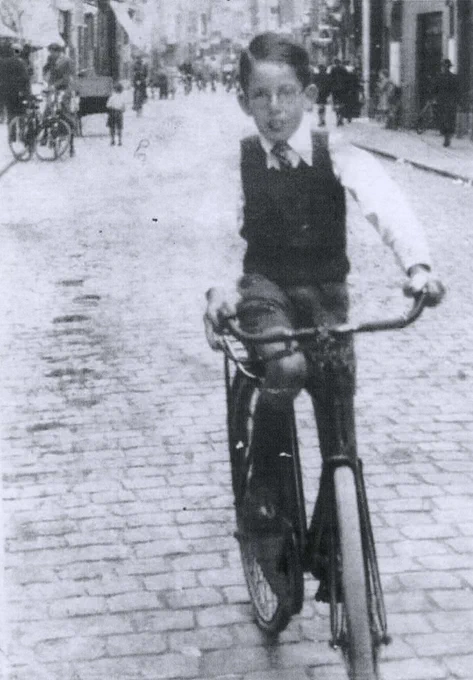 A young boy riding a bicycle down a cobblestone street.
