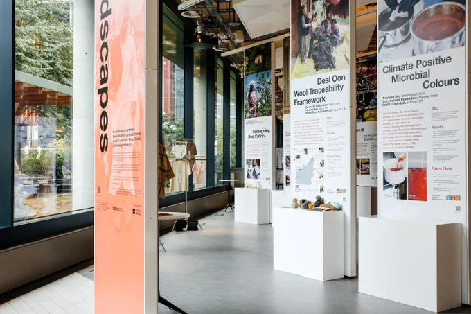 Modern exhibition space with tall panels and white pedestals.