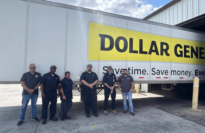 Group of people standing in front of a Dollar General truck. 