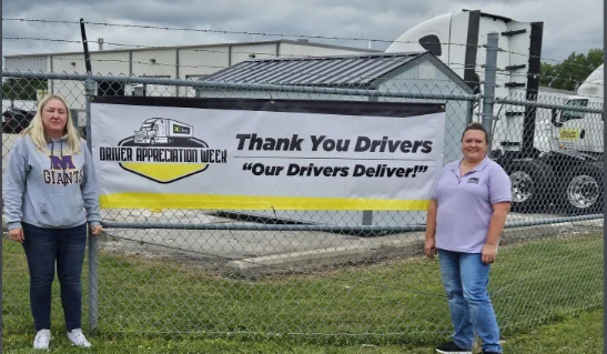 2 people standing in front of a white and yellow Dollar General sign.