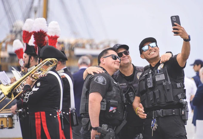 Three Port Police officers smiling together in a selfie, with a foggy, mist-filled backdrop at the Port of Los Angeles.