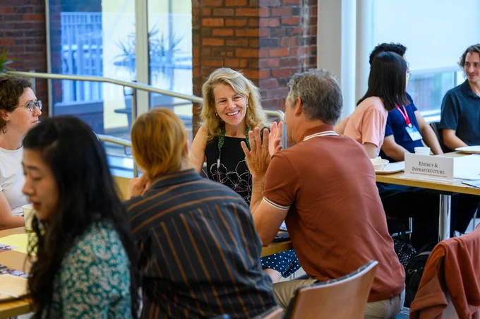 Event participants sitting around tables have animated conversation.