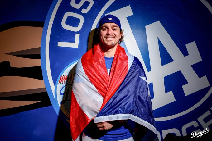 A photo of Kiké Hernández posing with the Puerto Rican flag in front of a Dodger mural.