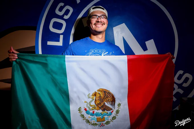 A photo of Anthony Banda posing with the Mexican flag in front of a Dodger mural.