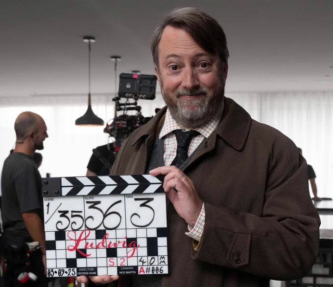 David Mitchell stands in costume as Ludwig, holding a clapperboard signalling the start of filming on series 2