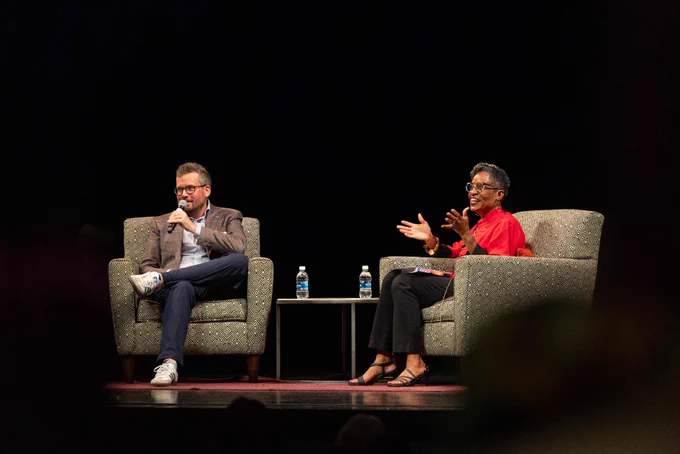Author John Green sits next to KU English professor Giselle Anatol in armchairs on the Lied Center's stage.