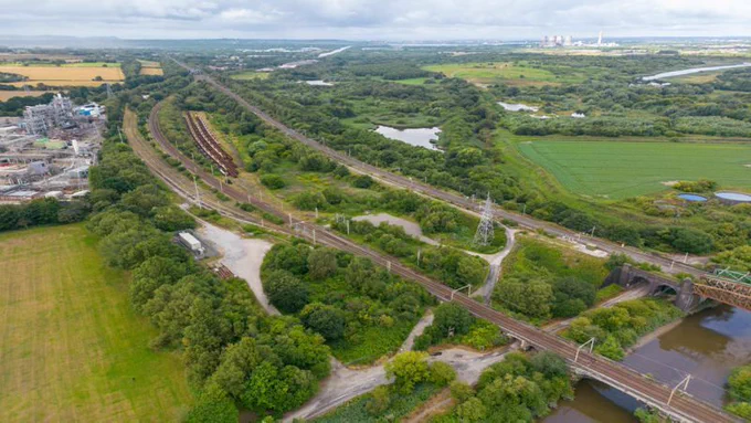 aerial view of train tracks surrounded by green fields.