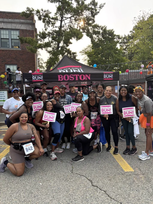 Rep. Pressley at a tent surrounded by a group of women runners holding signs that say “Black Women Run.”