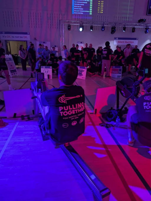 Picture of a man rowing on a rowing machine with blue red and purple lights shining on him