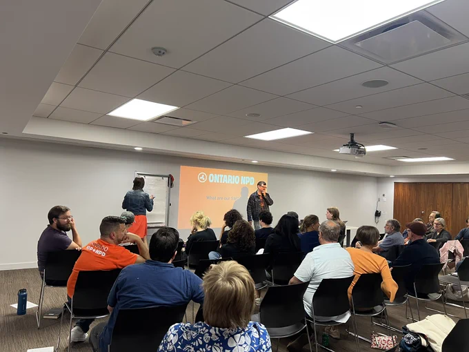 NDP members in a meeting room listening to John Nuttall