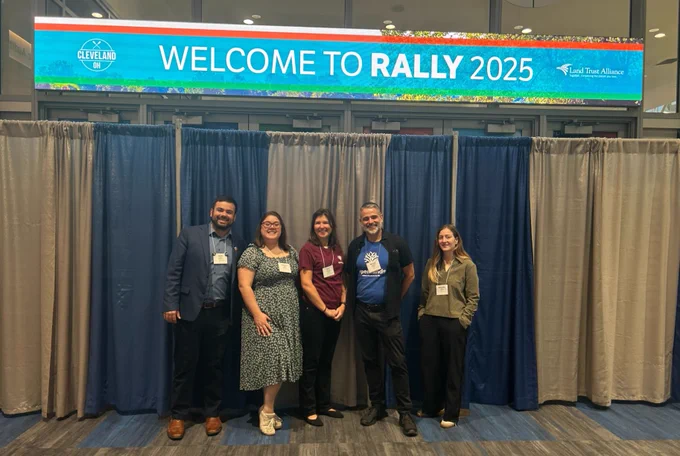 Openlands staff standing in front of the the Rally 2025 digital banner. CEO Michael Davidson is among 4 members of this staff.