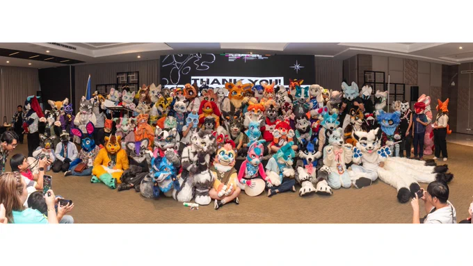 A panorama image of @BarkadaCon's fursuiter stage gathering featuring many suiters.