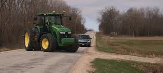 Farm tractor turning left into a field from a rural road