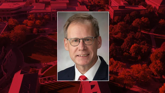 A color portrait of Mark Button on a red campus background.