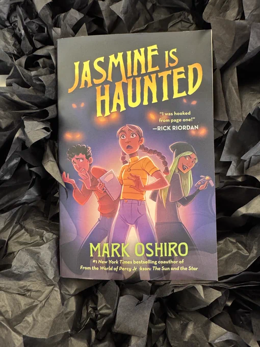 A copy of Jasmine is Haunted by Mark Oshiro resting on a background made up of black tissue paper.