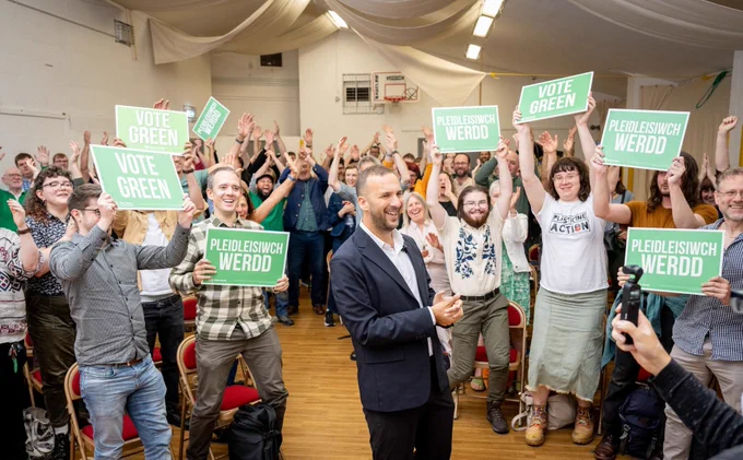 Zack at a green party event with lots of cheering.