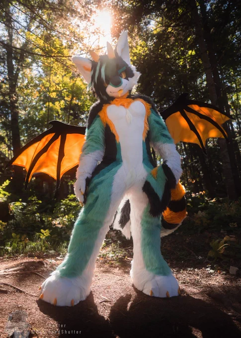 Cute dragon fursuit standing in the sun in a forest
