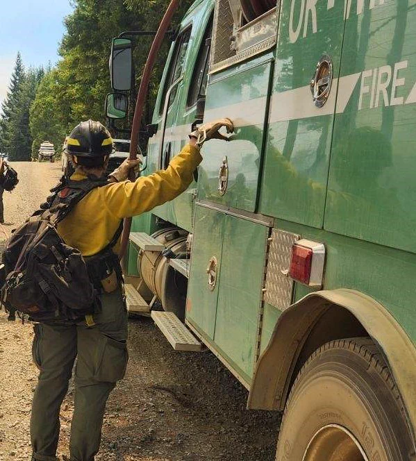 A firefighter stands next to an engine.