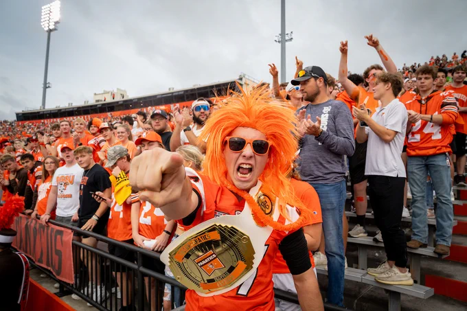 Student in orange BGSU attire cheering at a BGSU football game 