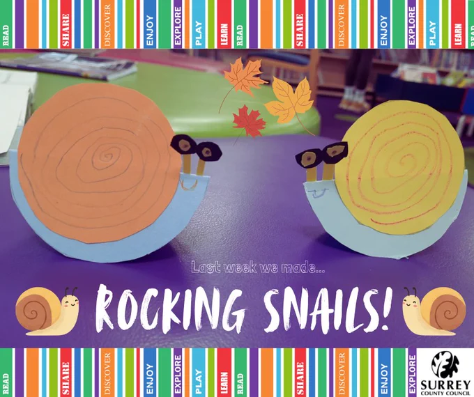 A photo of two paper snails sitting on a purple stool in the the children's section of Godalming Library with text. 'Last week we made... Rocking Snails!' The Surrey County Council logo is in the corner of the image. 