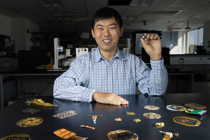 Wubin Bai holds a small health care apparatus, about the size and shape of an SD card