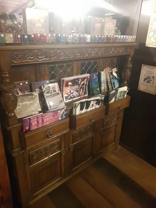 A china cabinet with RPGs filling the drawers and dice clustered along the top.