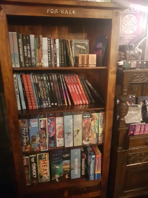 Bookshelf filled with RPGs and board games with the words 'For Sale' above the top shelf.