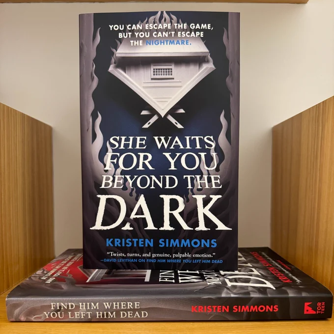 A paperback copy of She Waits For You Beyond the Dark standing on top of a copy of Find Him Where You Left Him Dead, both by Kristen Simmons.