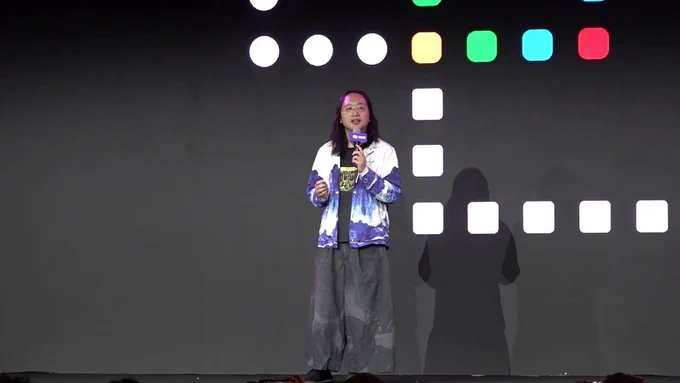 Audrey Tang, Taiwan’s cyber ambassador, first digital minister and architect of the Taiwan Model of digital diplomacy, delivers remarks while standing in front of the logo for collaborative book project ⿻ 數位 Plurality: The Future of Collaborative Technology and Democracy.