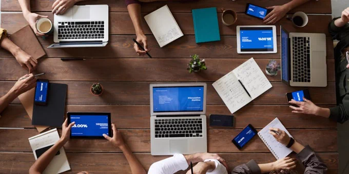 Overhead view of a diverse team in a business meeting using laptops and tablets.
