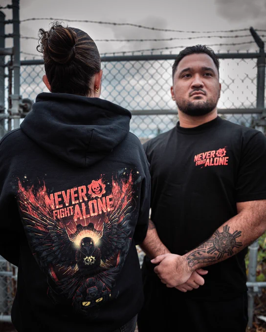 Two people wearing black t-shirts with the Never Fight Alone logo on the back.
