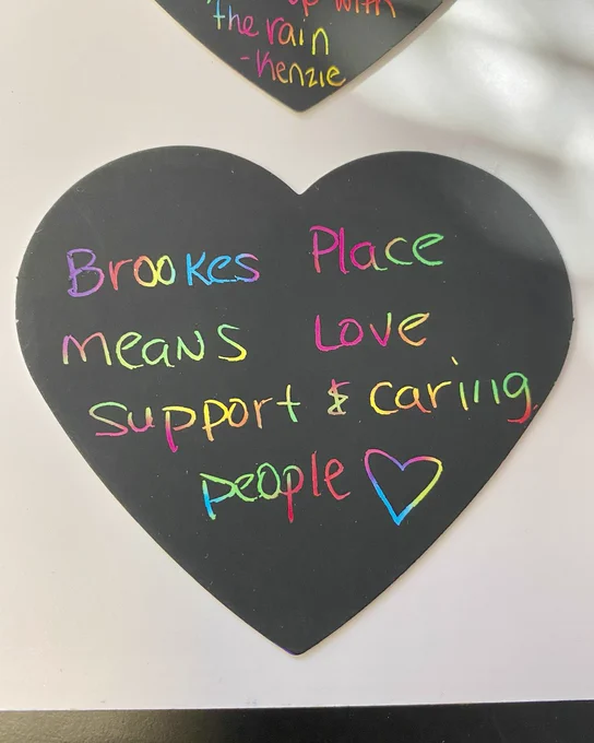 Heart-shaped blackboard with colorful chalk writing saying 'Brookes Place means love, support & caring people' and a heart drawing.