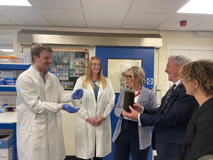 Two researchers in white lab coats speak to Climate Action Secretary Gillian Martin and Professor Bill Austin  in a laboratory as another person looks on from the side