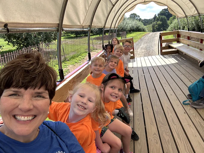 mrs. anders snaps a selfie of herself and 8 students on the tractor ride through the orchard 