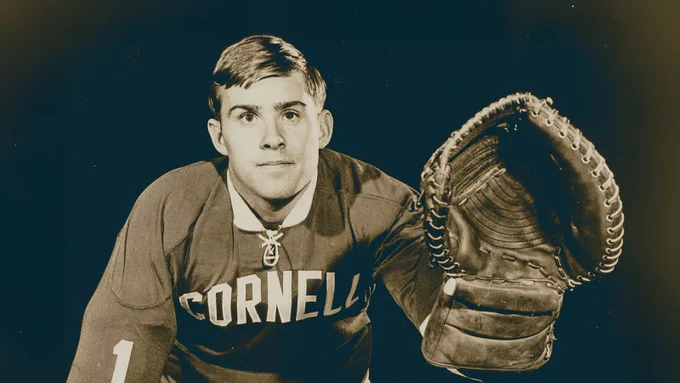 Vintage sepia-toned photo of hockey legend and Cornell University goalie Ken Dryden '69 wearing a hockey jersey and holding a large goalie glove.