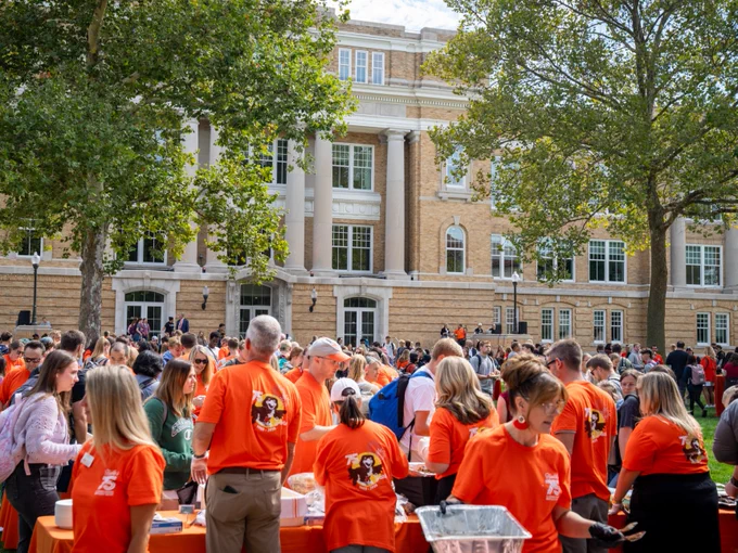 A large group of people at the All-Campus Picnic with University Hall in the background. 