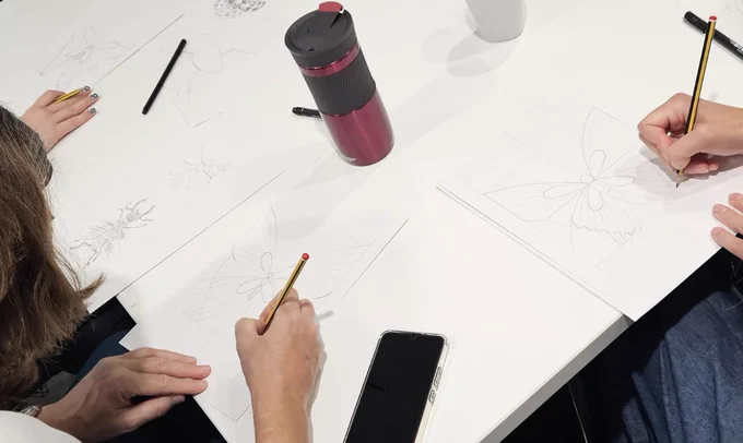 Close up of delegates drawing insects at the insect art workshop