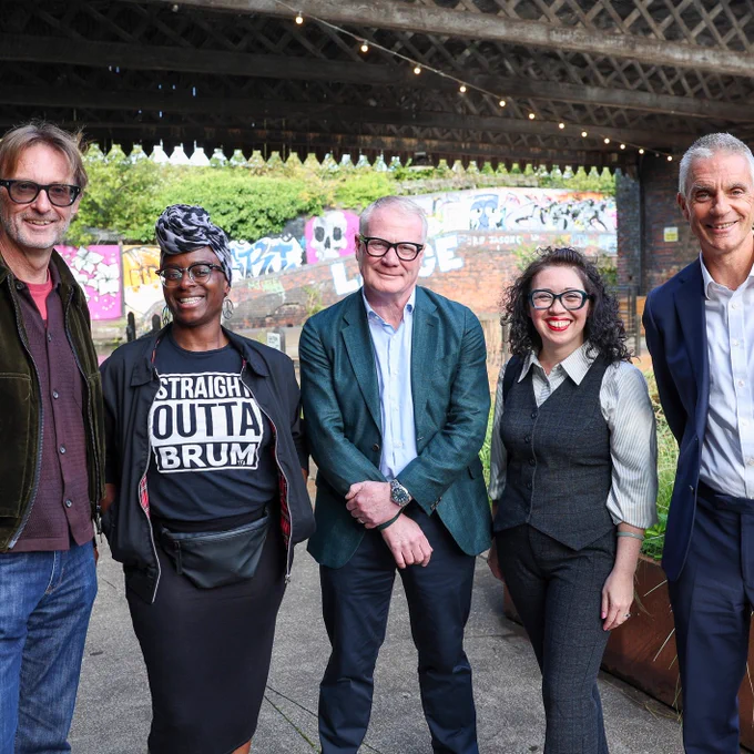 Five people (three men and two women) stood next to each underneath a bridge. 